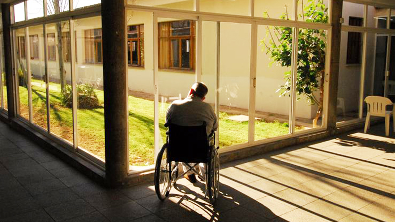 Hombre en silla de ruedas observando un patio interior
